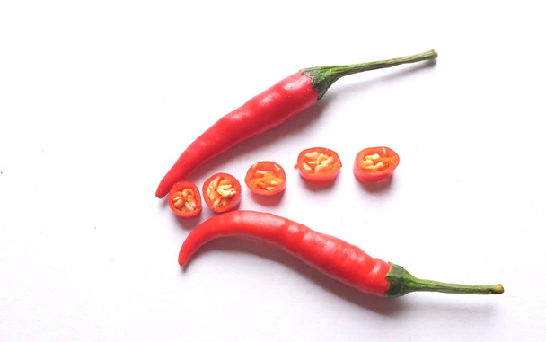 Rijp rode hete chili pepers gesneden in stukken groenten geïsoleerd op witte achtergrond.koken ingrediënten - Foto, afbeelding