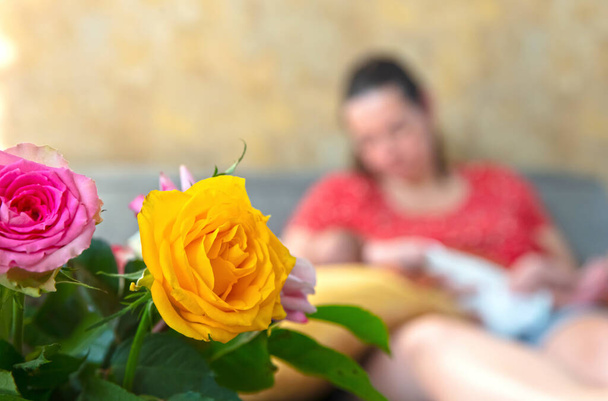 Mother with her baby in the background, selective focus on yellow flower - 写真・画像