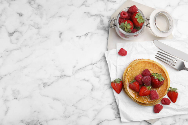 Tasty pancakes served with honey and berries on white marble table, flat lay. Space for text - Foto, Imagen