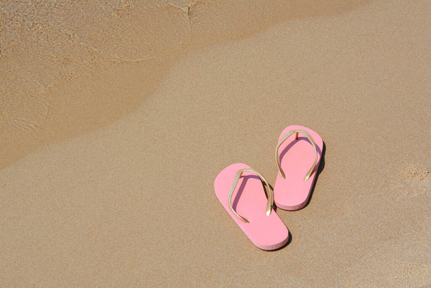 Stylish pink flip flops on wet sand near sea, space for text - Foto, Bild