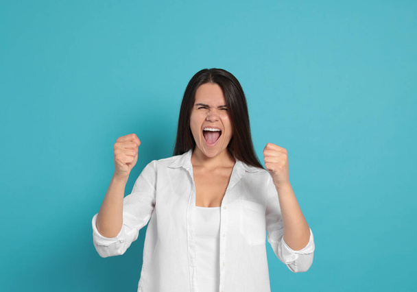 Aggressive young woman shouting on turquoise background - Photo, Image