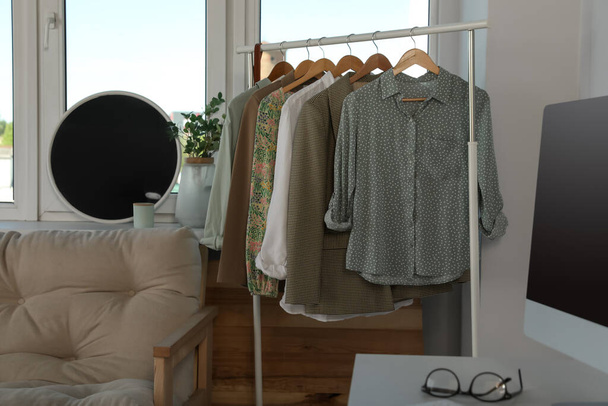 Rack with stylish clothes near window indoors. Interior design - Foto, Imagen