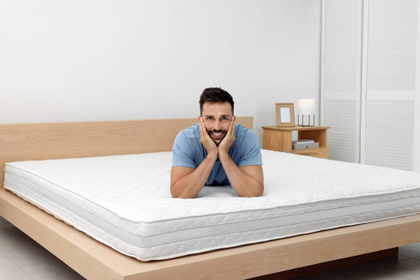Happy man on bed with comfortable mattress at home - Zdjęcie, obraz