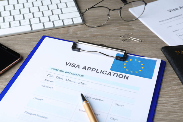 Visa application form for immigration to European Union, pen and glasses on wooden table, closeup - Фото, изображение