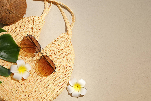 Flat lay composition with stylish sunglasses and wicker bag on sand. Space for text - Fotó, kép
