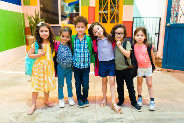 Happy mixed-race group of kindergarten children carrying backpacks while going to preschool  - Photo, Image