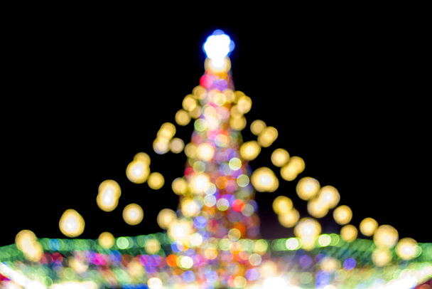 Large New Years Christmas tree decorated with luminous multi-colored garlands and illumination at night. Christmas tree with flashing lights. Blurred background. New Year and Christmas holidays - Photo, Image