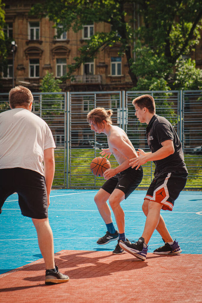 Львів (Україна) 28 травня 2022: чоловіки грають у баскетбол на відкритому повітрі сонячний літній день. - Фото, зображення