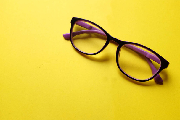 copy space a purple framed eyeglasses isolate on a yellow background - Zdjęcie, obraz