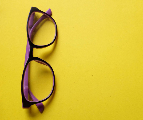 copy space a purple framed eyeglasses isolate on a yellow background - Foto, imagen