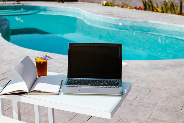 laptop, notepad and cool drink by the pool, working from home - Foto, immagini
