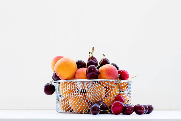 Сладкие вишни с абрикосами изолированы на белом фоне. Спелые ягоды крупным планом. Смешайте ягоды и фрукты. - Фото, изображение