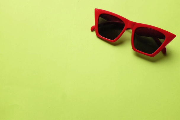 copy space a red frame sunglasses isolate on a green background.accessories modern women's fashion - 写真・画像