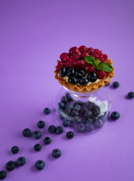 desszert friss áfonyával, málnával és mentával lila alapon - Fotó, kép
