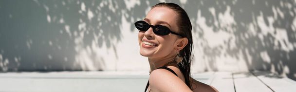 весела молода жінка з мокрим волоссям і стильними сонцезахисними окулярами, купається зовні, банер
 - Фото, зображення