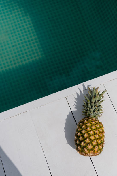 top view of tropical and sweet pineapple near blue water in swimming pool  - Φωτογραφία, εικόνα