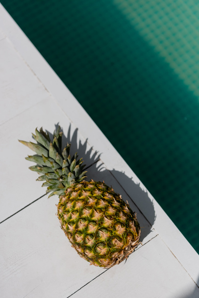 Blick von oben auf tropische und reife Ananas in der Nähe von blauem Wasser im Schwimmbad  - Foto, Bild
