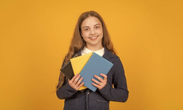 smiling child hold school book on yellow background, homework. - Photo, image