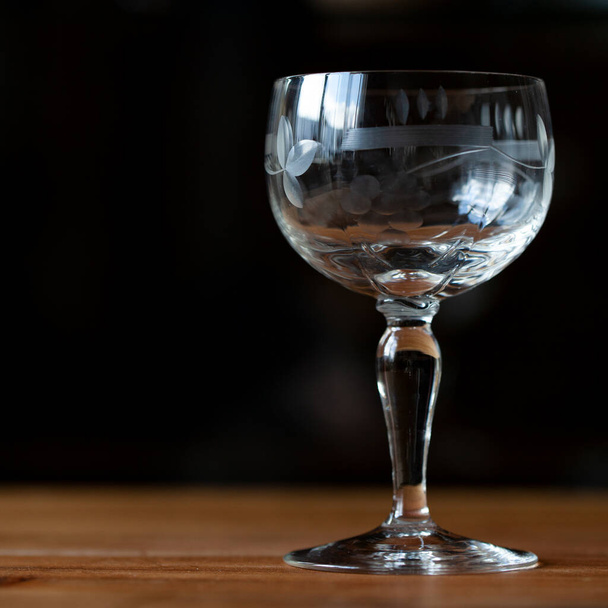 antique transparent glass wine glass on a black background. crystal glass with engraving. glass close-up - Foto, Imagem