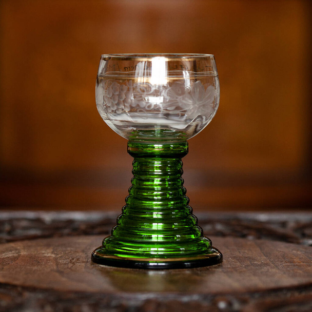 green glass goblet of unusual shape in a luxurious interior. green goblet close-up. bohemian glass closeup - Foto, imagen