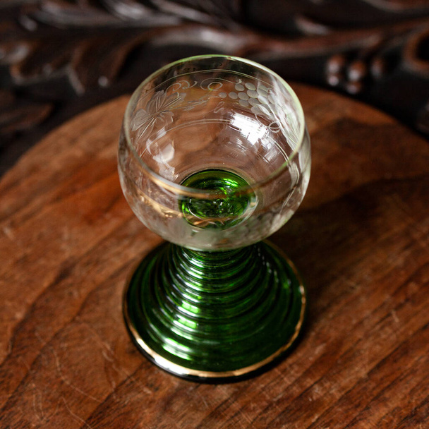 green glass goblet of unusual shape in a luxurious interior. green goblet close-up. bohemian glass closeup - 写真・画像