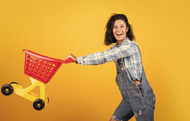 Quality service. female shopper with trolley in supermarket. woman shopping in supermarket pushing trolley. happy girl hold shopping cart. Buyer in supermarket. customer with empty cart. - Photo, image