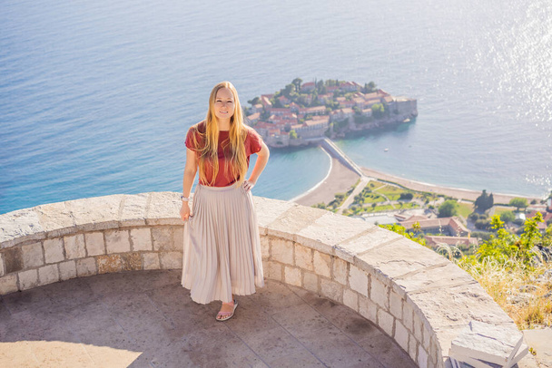 Woman tourist on background of beautiful view of the island of St. Stephen, Sveti Stefan on the Budva Riviera, Budva, Montenegro. Travel to Montenegro concept. - Photo, Image
