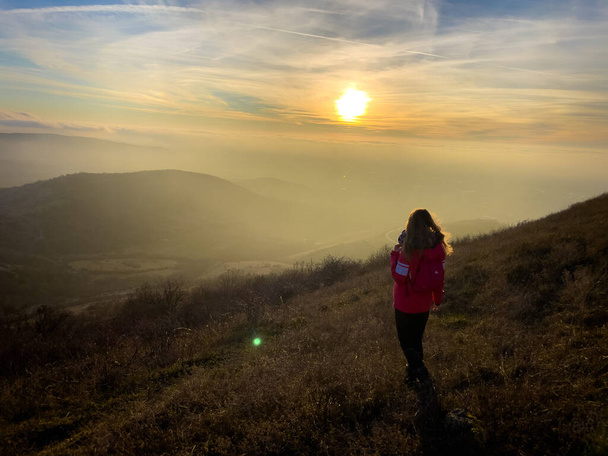 Woman hiker standing on top of a hill and admiring the sunset in winter - Foto, Imagen