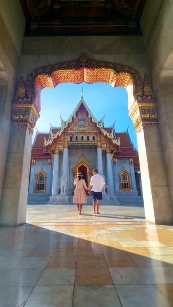 Wat Benchamabophit мраморный храм, является королевским храмом в столице Таиланда Бангкоке. пара азиатских женщин в шляпе и европейских мужчин, посещающих храм в Бангкоке - Кадры, видео
