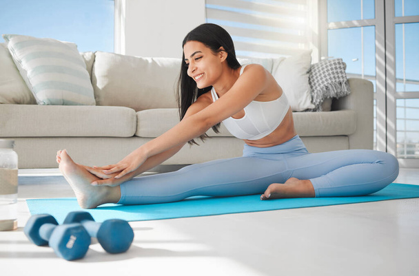 a sporty young woman stretching while exercising at home. - Foto, Imagem