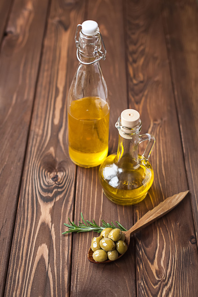 Green olives and olive oil on wooden table - Valokuva, kuva