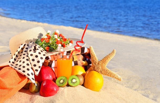 Sombrero de mujer, diferentes frutas, estrellas de mar y vaso de jugo en el
 - Foto, Imagen