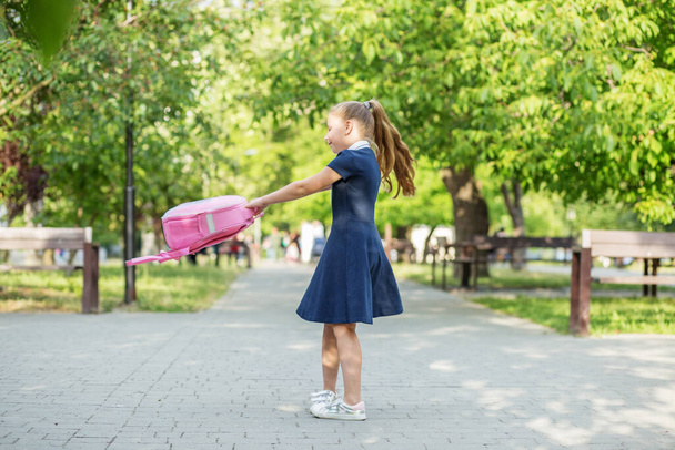 Schoolgirl goes from school and twirls with backpack. Children are having fun. Concept of back to school, learning, friendship and childhood. - Фото, изображение