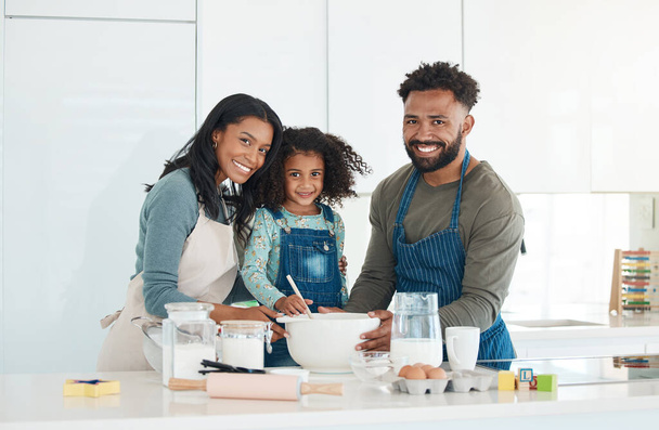 Cropped portrait of an affectionate young couple and their daughter baking in the kitchen at home. - Photo, Image