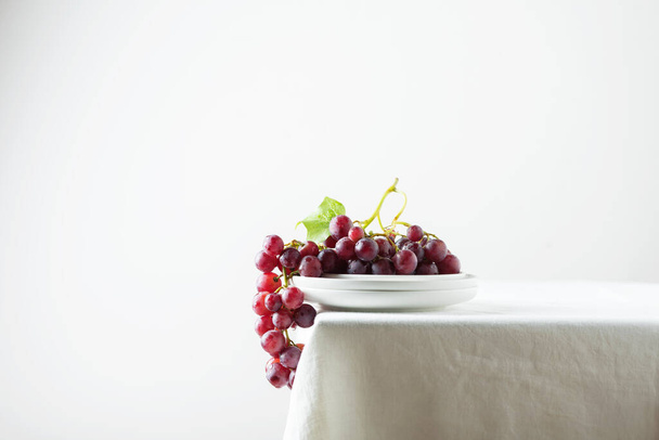 Red grape on the white linen tablecloth, selective focus image - 写真・画像