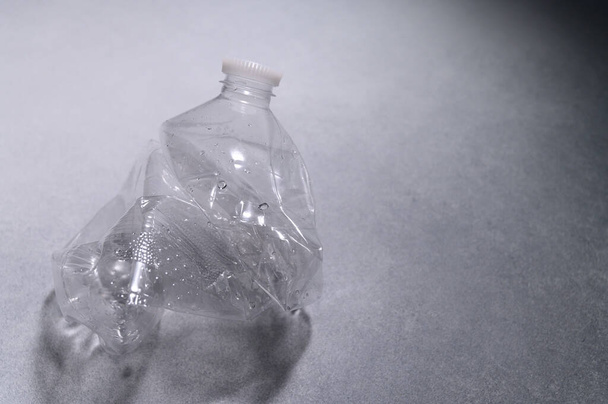 Crumpled Plastic Bottle on Light Wall. Recycling of Garbage, Plastic. Ecological Problem, Global Environment. Top View, Flat Lay. - Foto, imagen