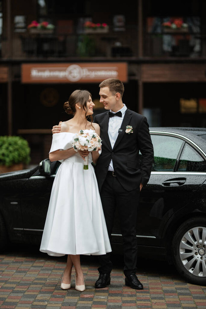 young couple bride and groom in a white short dress walking in the rain - Foto, Bild