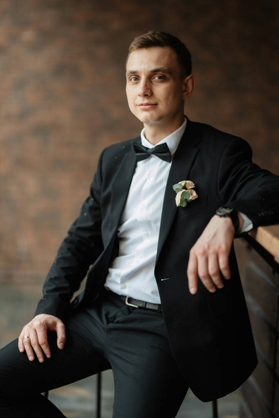 portrait of a young guy groom in a black suit on a rainy day - Fotografie, Obrázek