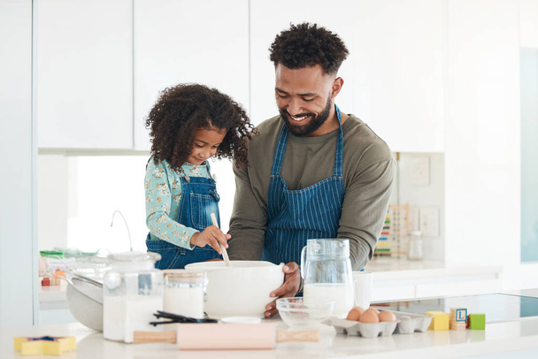 a handsome young man and his daughter baking in the kitchen at home. - Foto, Imagen