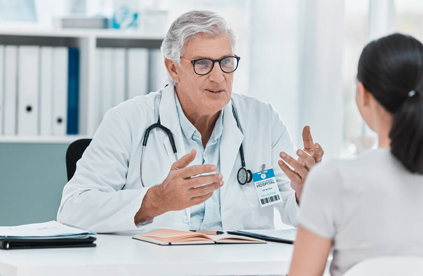 Dies ist eine häufige Reaktion. ein reifer Arzt sitzt mit seinem Patienten während einer Konsultation in seiner Klinik - Foto, Bild