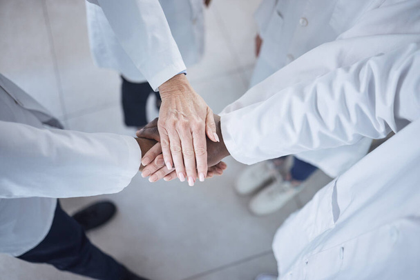 Group of unrecognisable scientists stacking and joining hands in unity and support while standing in a lab at work. Diverse group of lab workers piling their hands from above. - Foto, Bild