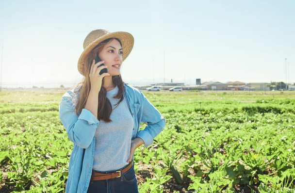 a young female farmer using her phone to make a call. - Foto, imagen