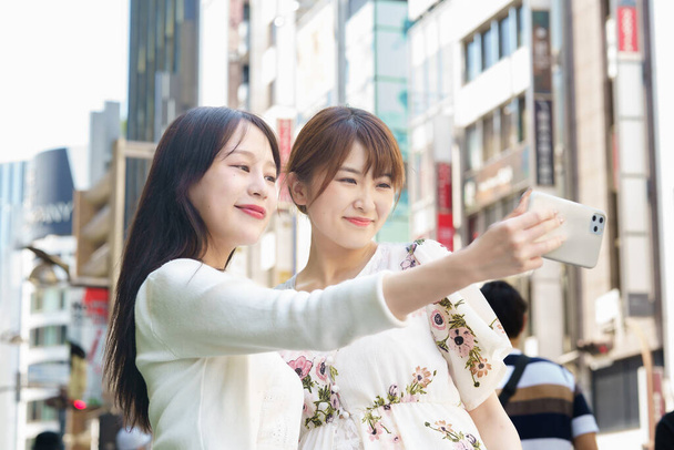 Two young women taking selfies in the city - Φωτογραφία, εικόνα
