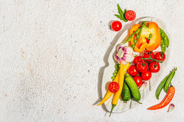 Harvest fresh vegetables on a serving plate. Vegan food concept, trendy hard light, dark shadow. Light plaster background, top view - Fotoğraf, Görsel