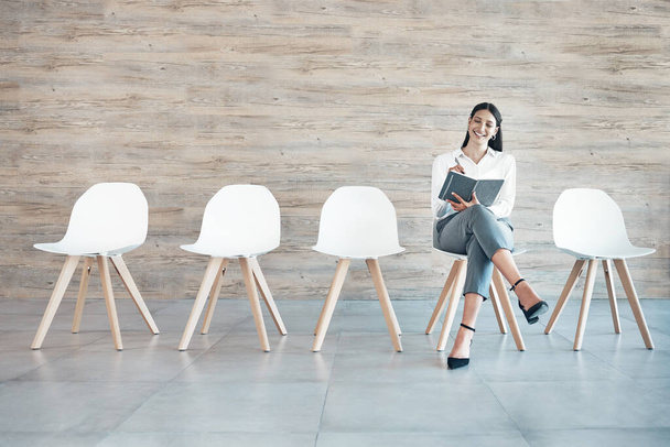 Full length shot of an attractive young businesswoman sitting alone in the office and using a notebook. - Photo, image