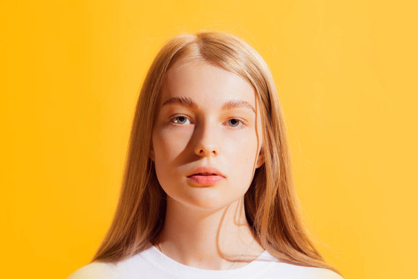 Serious. Closeup one young beautiful girl, student in casual style outfit isolated on bright yellow background. Concept of beauty, art, fashion, youth, healthy lifestyle. Copyspace for ads, text - Photo, Image