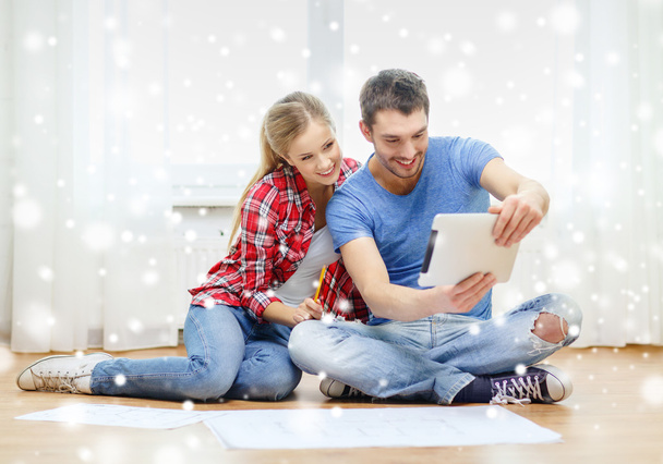 smiling couple with tablet and blueprint at home - 写真・画像