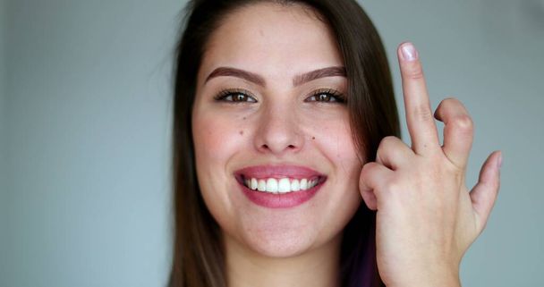Young woman giving middle finger, pretty girl with attitude shows offensive gesture while smiling - Foto, imagen