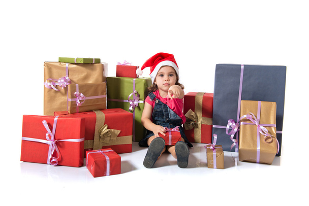 Blonde christmas kid around several presents pointing to the front - Фото, изображение