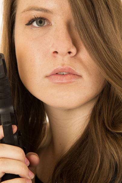 Close-up portrait of a woman holding a pistol with a serious exp - Foto, Imagem